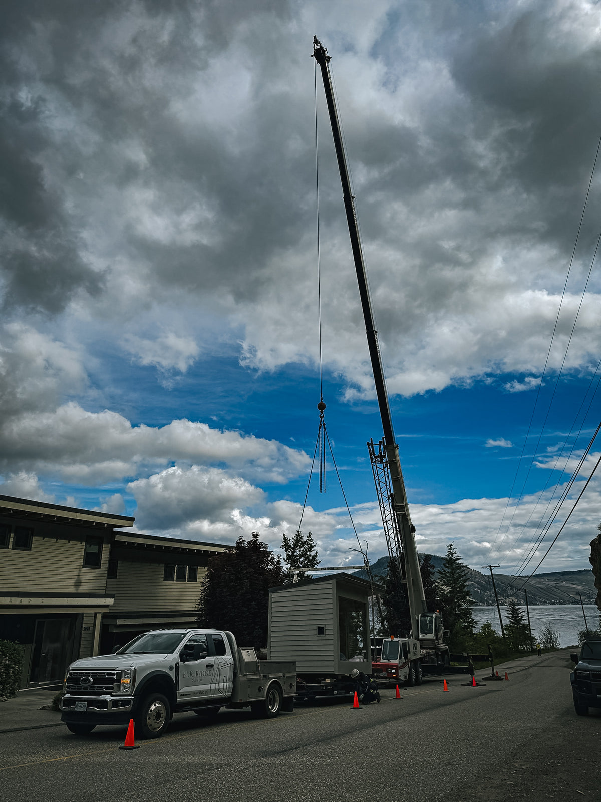 Alpha Cranes boom fully extended above the Elk Ridge Modular F-550 and trailer carrying a modular sauna