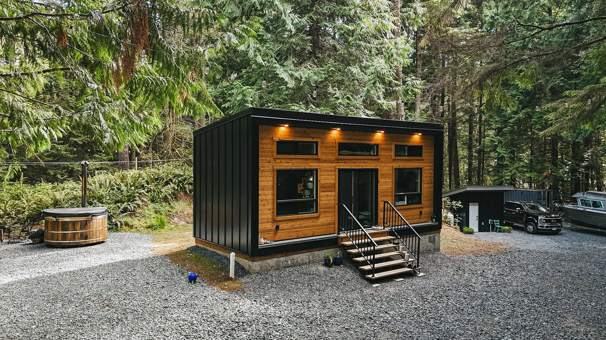 Finished 11.5′ × 27′ MODERN Cabin in black board and batten with cedar accents, set among old-growth trees near Sooke, BC
