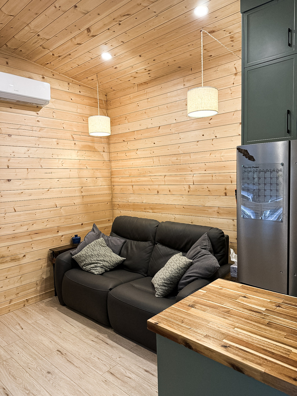Living space in a Modern Cabin with pine tongue-and-groove walls, a couch, and pendant lighting