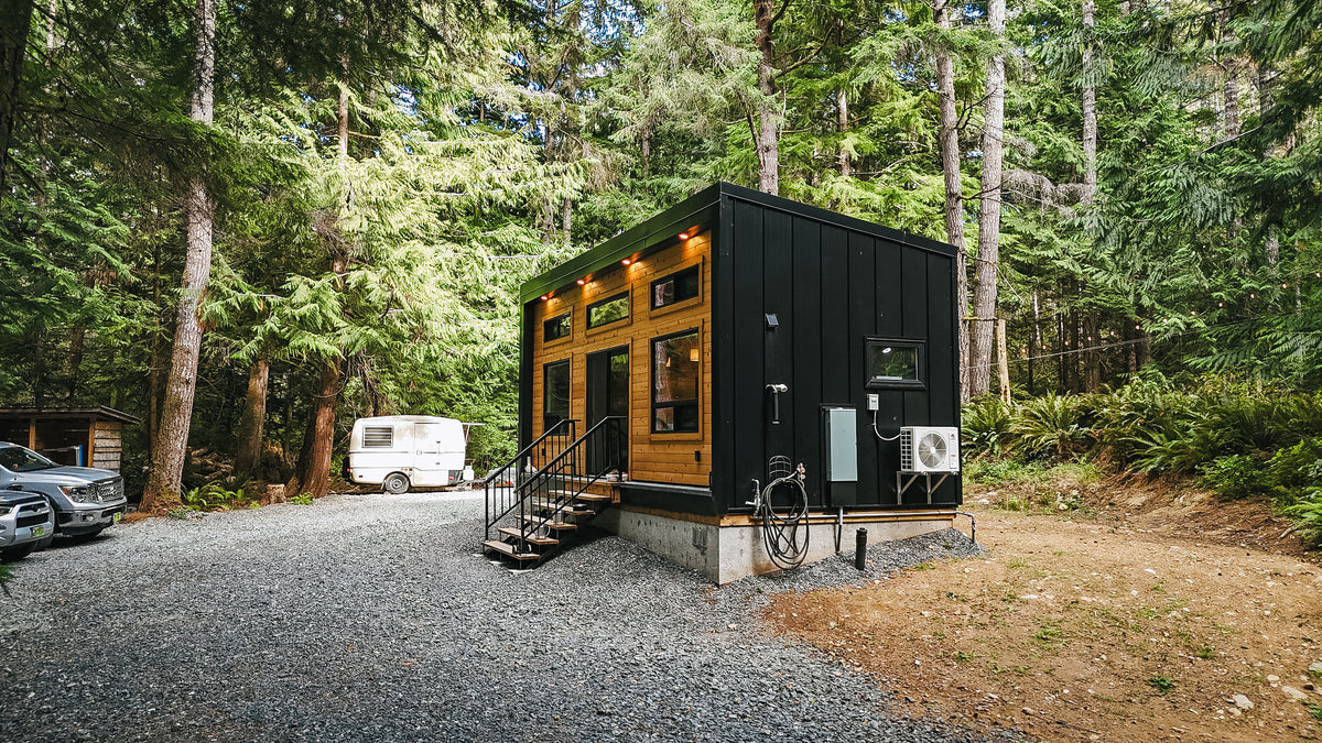 Side view of a modular Modern Cabin on a 4-foot concrete foundation with entry stairs, mini-split, and exterior lighting
