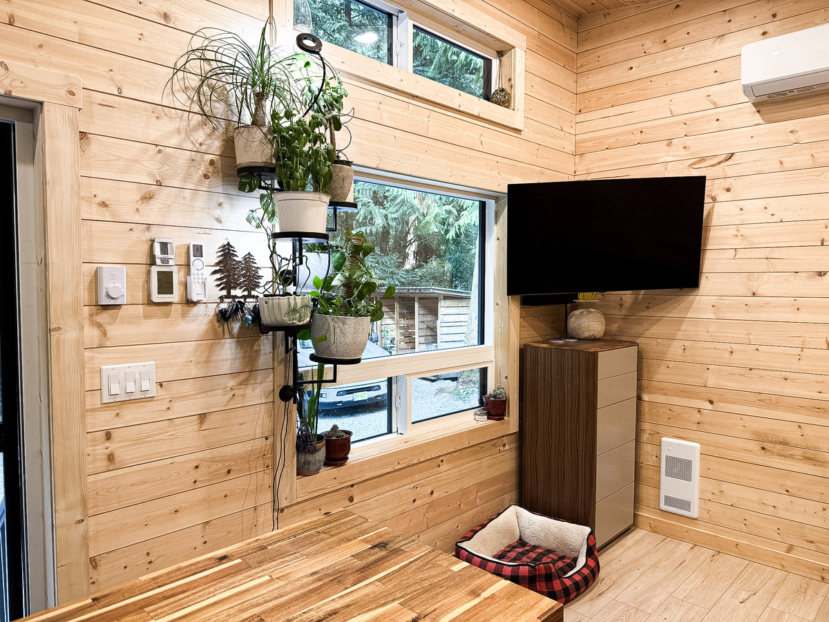 Cabin living area with windows, a wall-mounted TV, and a hanging plant rack