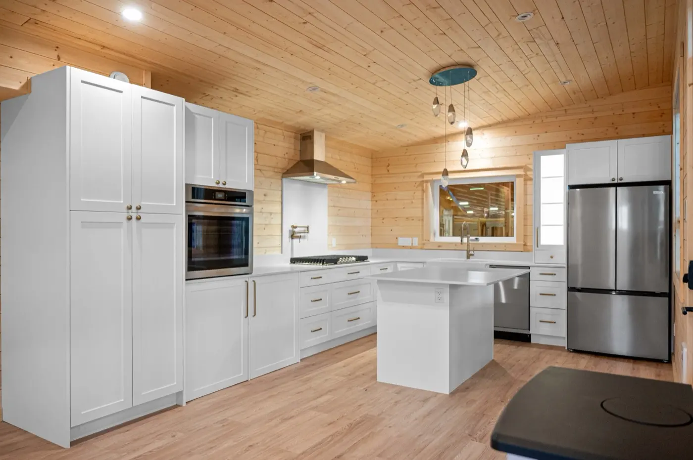 Finished Elk Ridge kitchen with white shaker cabinets, island and wood ceiling