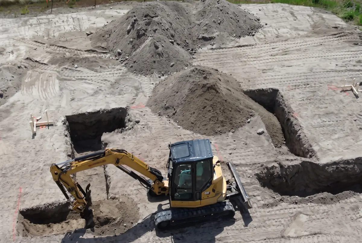 Excavator digging foundation footings on a home site