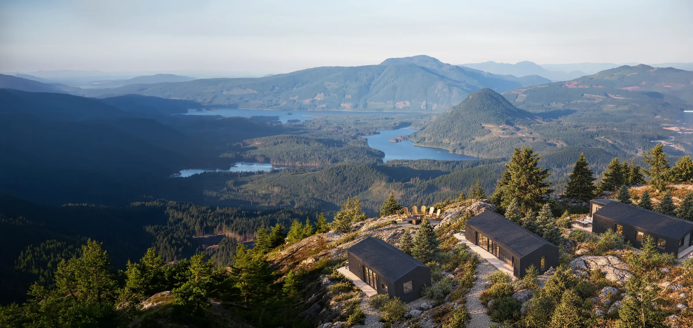 Three cabins on a rocky summit above a lake valley